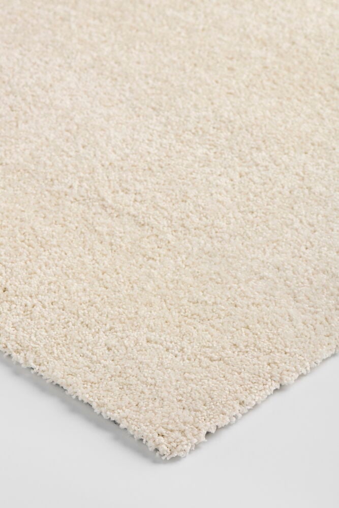 Närbild i vinkel av en lurvig Lizette matta i naturfärgad ljus kräm polypropen.