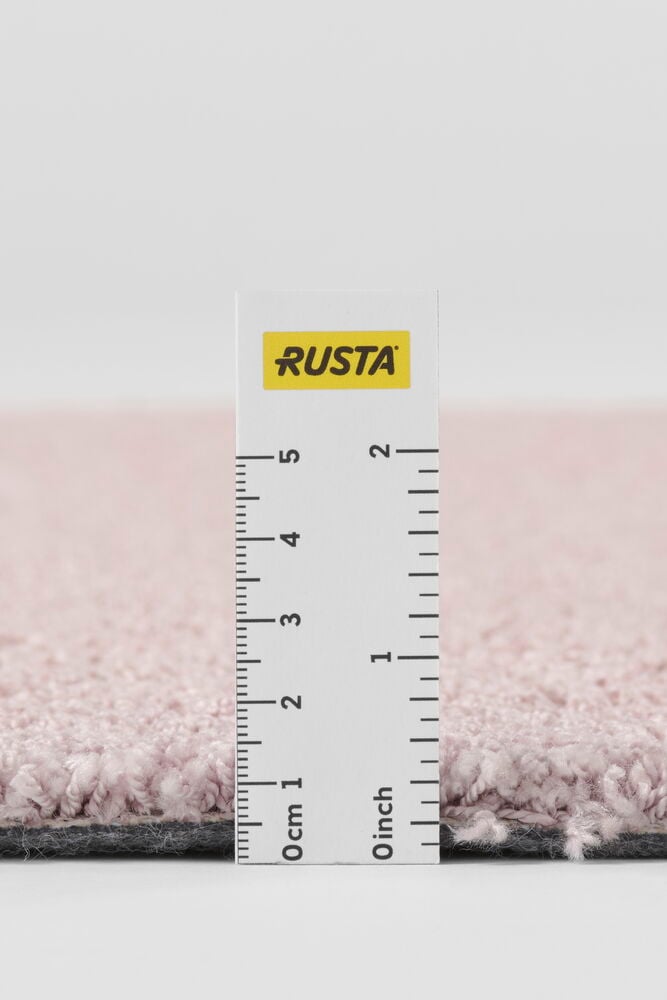 Närbild på en rosa polypropen Matta Lizette med linjal som visar tjockleken.