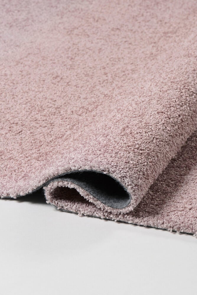 Närbild av Matta Lizette Rosa Polypropen, delvis upprullad med grå baksida.