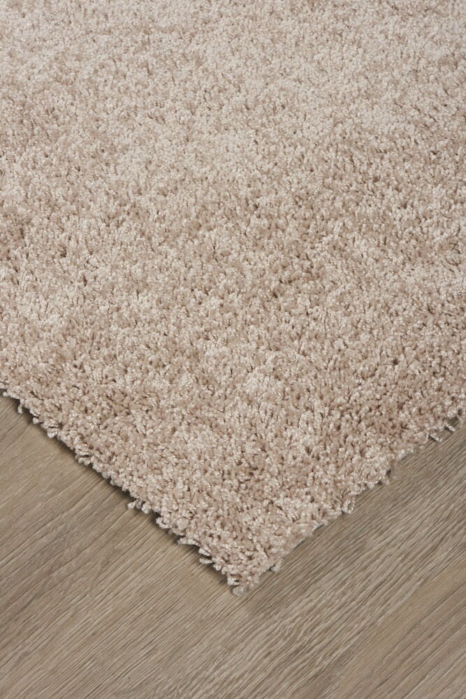 Beiger Teppich mit kurzem Flor auf Holzboden.