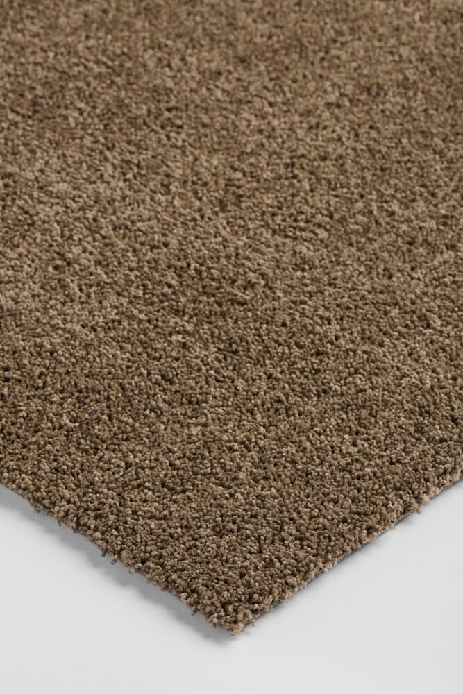 Kulmakuvaus lähikuva ruskeasta teksturoidusta Polypropeeni Matto Lizette -matosta valkoisella pinnalla.