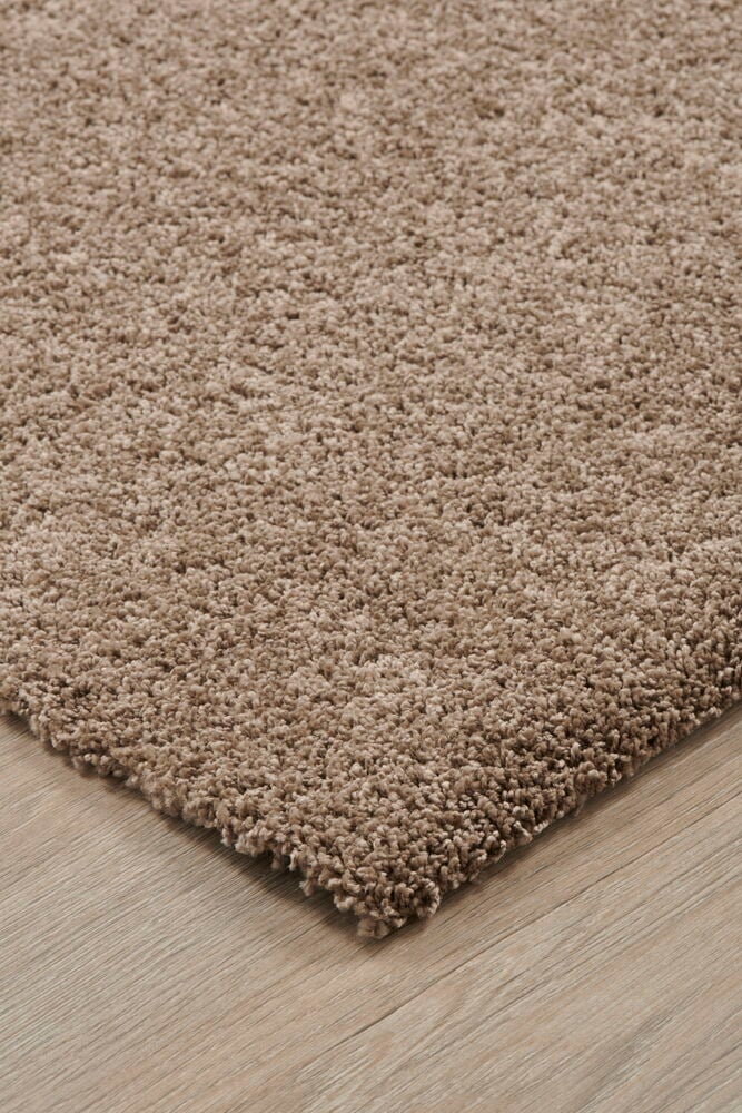 Brauner glänzender Teppich auf Holzboden mit weichem Flor.