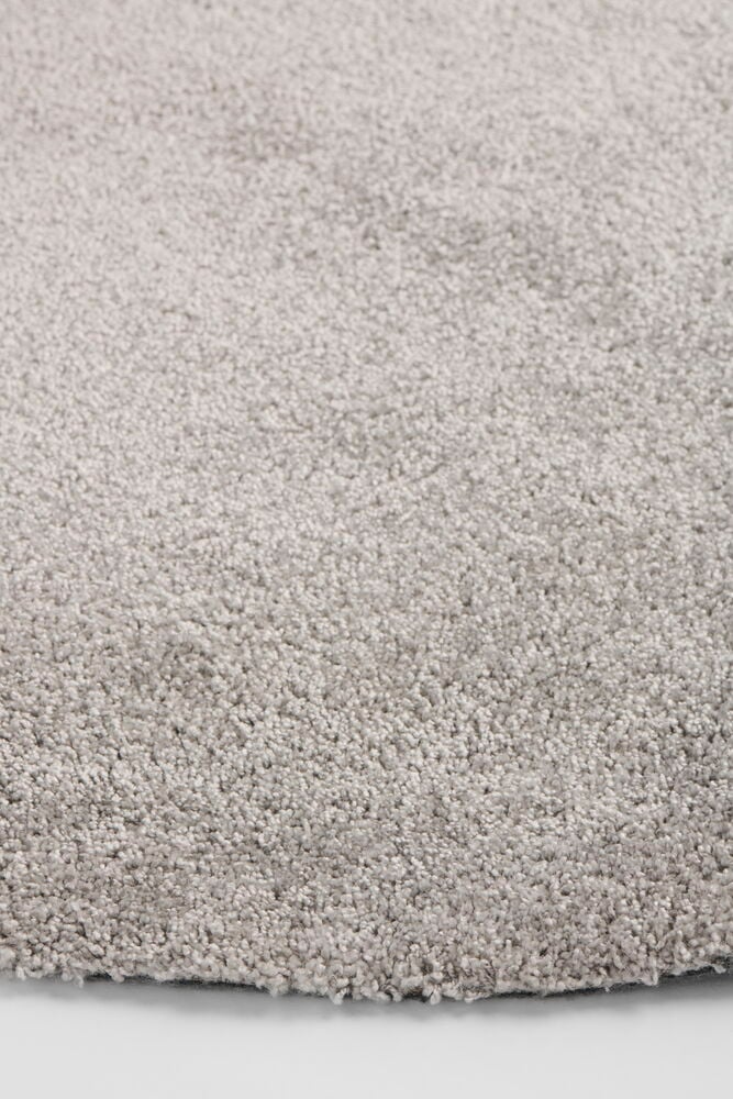 Nahaufnahme eines runden, grauen Lizette Ø133 cm Polypropylen-Teppichs mit flauschiger Textur.
