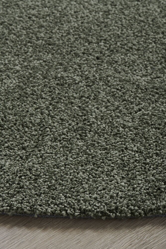 Runder grüner Teppich mit kurzem glänzendem Flor.