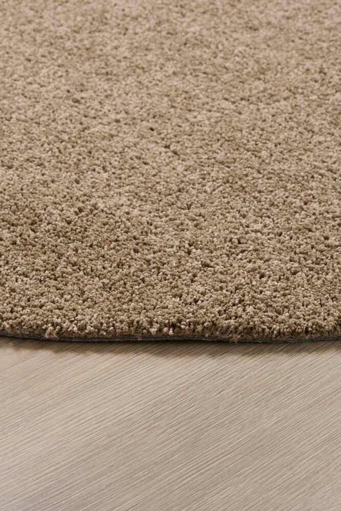 Runder brauner Teppich mit kurzem Flor auf dem Boden.