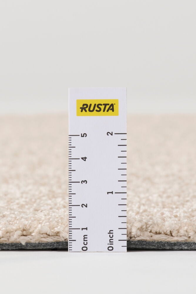 Lähikuva beigestä polypropeenista Matto Lizettestä, joka esittää sen tekstuuria ja paksuutta viivaimen kanssa.