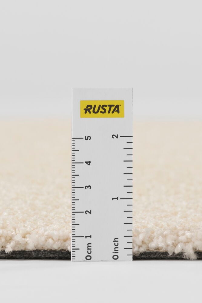 Lähikuva Matto Lizette Luonnonvärinen Polypropeeni, kermanvärinen teksturoitu nukka, tumma pohja, mitattuna viivaimella.