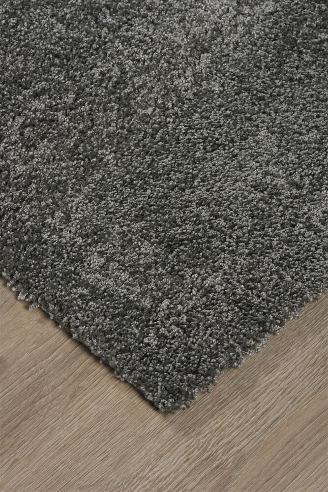 Tummanharmaa matto lyhyellä nukalla puulattialla.