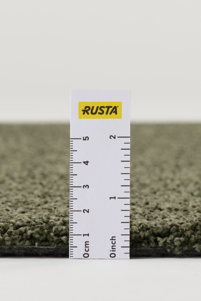 Lähikuva vihreästä Matto Lizette -nimisestä matosta sivulta, viivain mittaa sen nukan paksuutta.