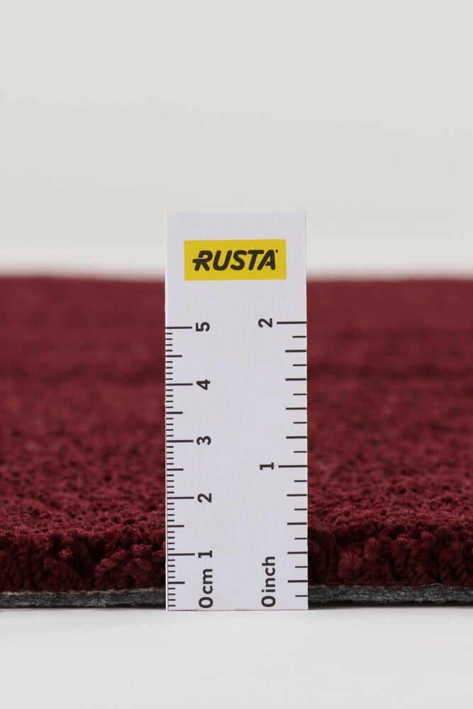 Närbild sidovy av en texturerad vinröd polypropen Matta Lizette, med linjal som visar tjockleken.