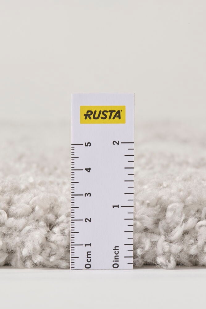 Lähikuva harmaasta nukkamatosta Elin, jossa viivain näyttää sen pehmeän nukan korkeuden.