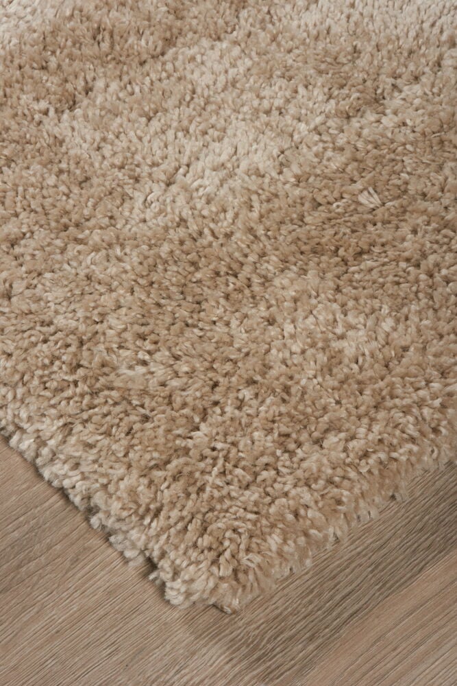 Närbild på en raggig beige Elin Polypropen matta som ligger på ett ljust trägolv, sedd i vinkel.