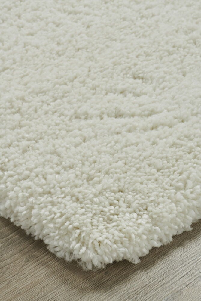 Vit ryamatta med tjock lugg på trägolv.
