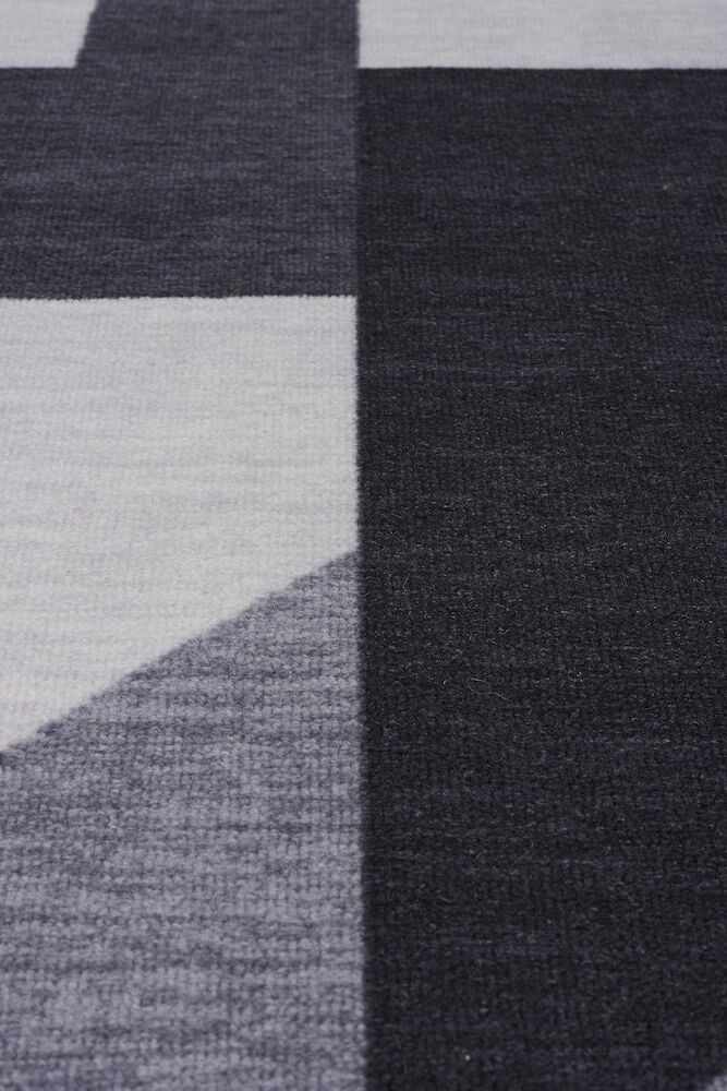 Svart och grå matta med abstrakt blockmönster.