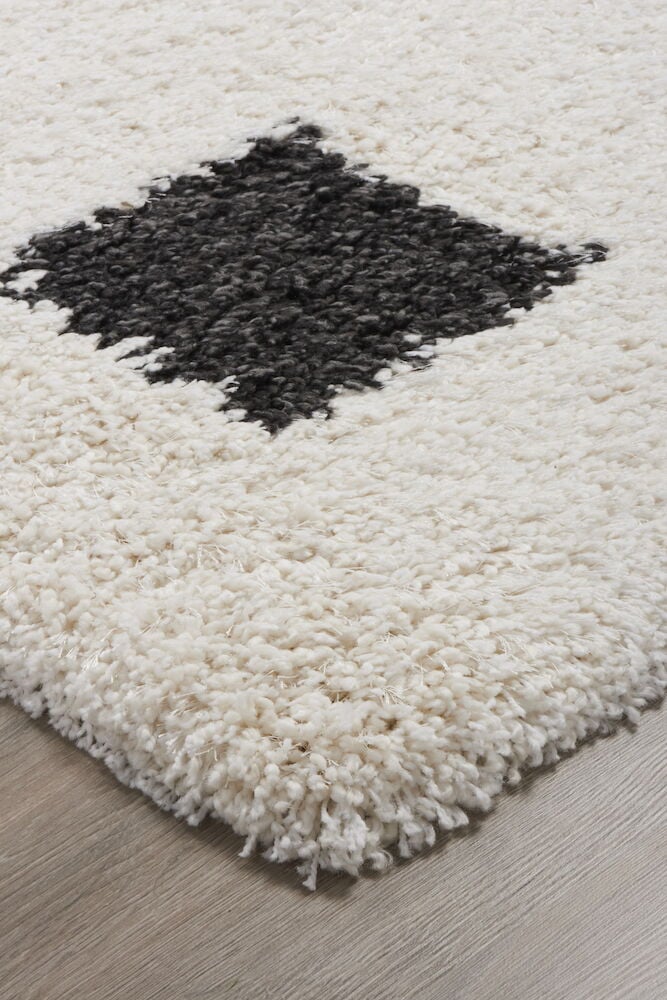 Mjuk svartvit matta med rutmönster på trägolv.