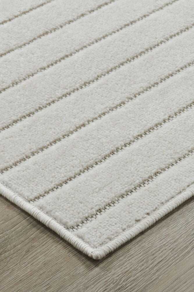 Off-white matta med randigt mönster på golv.