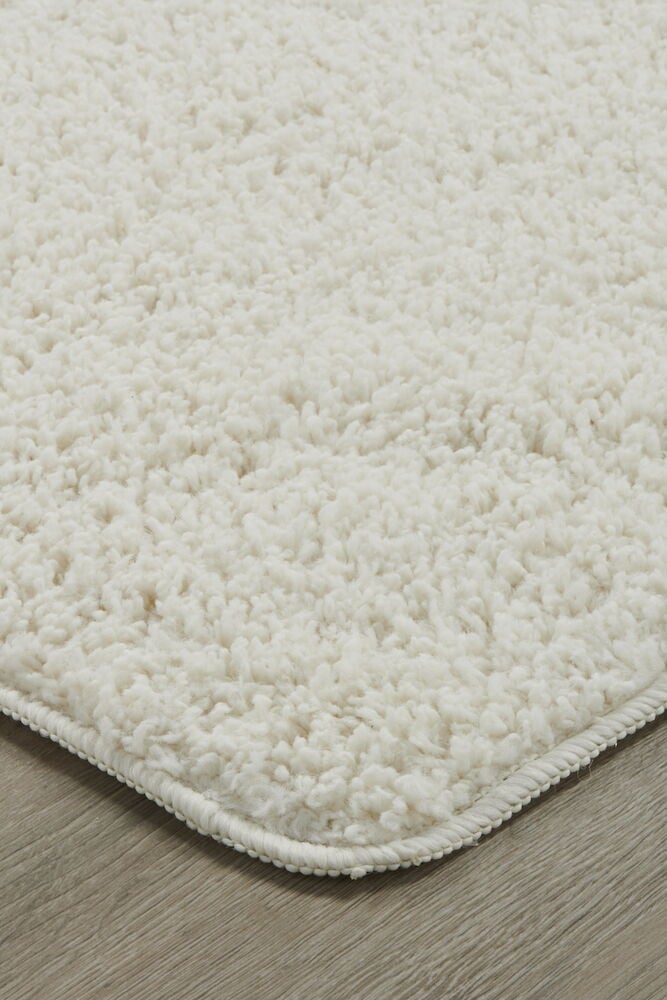 Nahaufnahme eines weißen weichen Flokatis auf Holzboden.