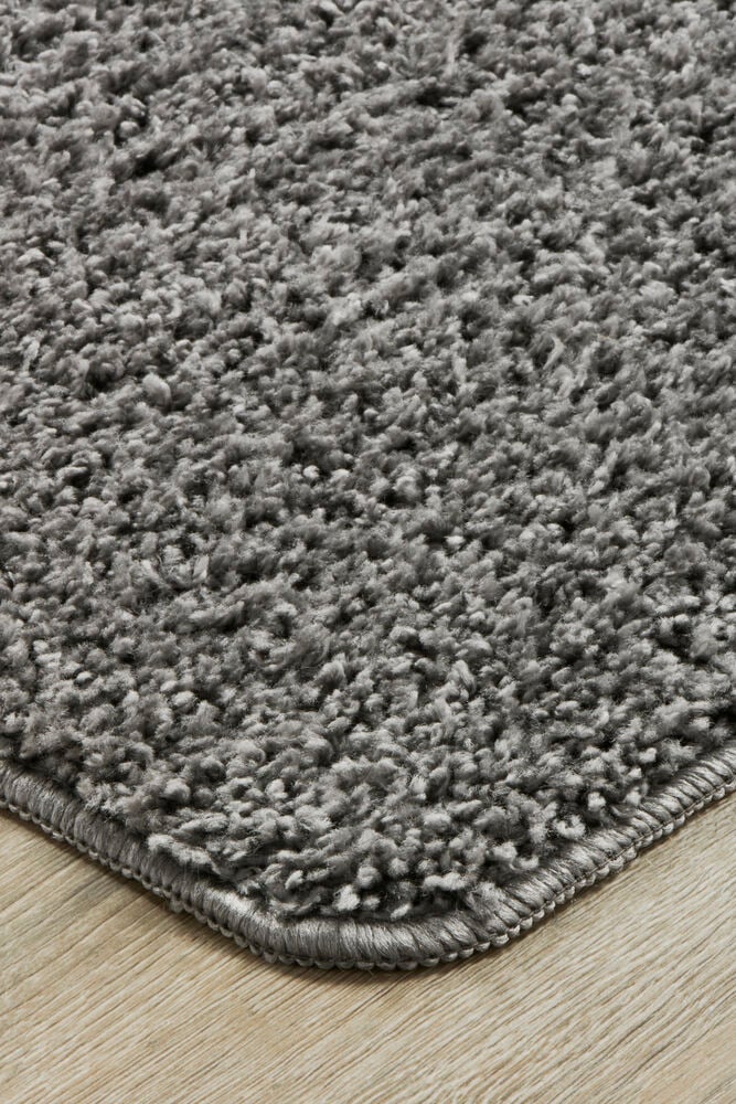 Grauer weicher Teppich mit Struktur auf Holzboden.