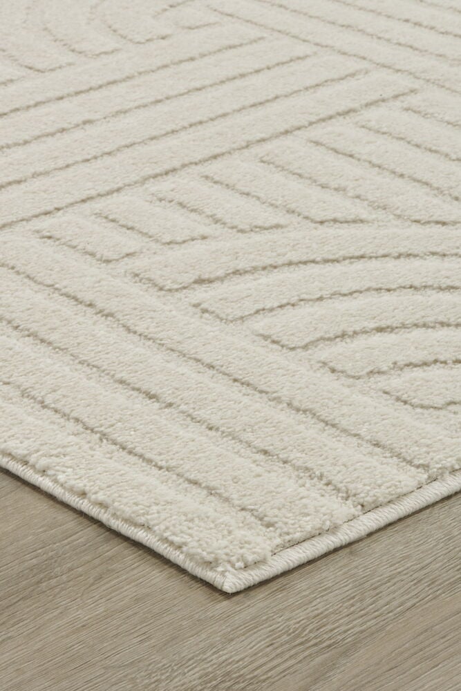 Heller cremefarbener Teppich mit grafisch erhabenem Muster.