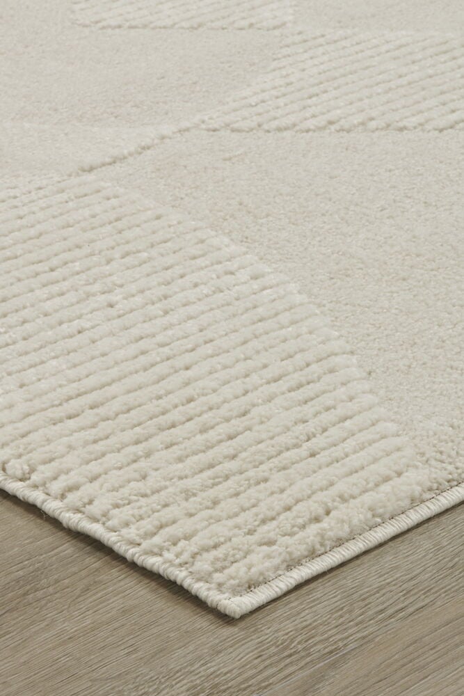 Heller cremefarbener Teppich mit weichen wellenförmigen Mustern.