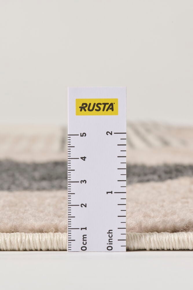 Lähikuva Matto Linasta, beigestä polypropeenimatosta harmailla raidoilla, mitattuna viivaimella sen paksuuden näyttämiseksi.