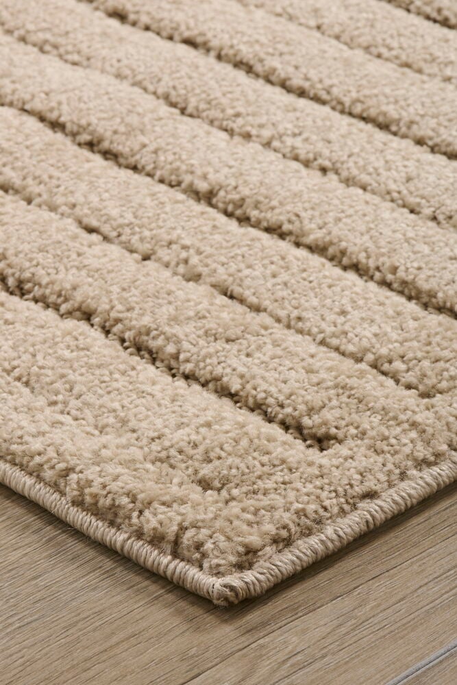 Rektangulär beige matta med tjock lugg på golv.