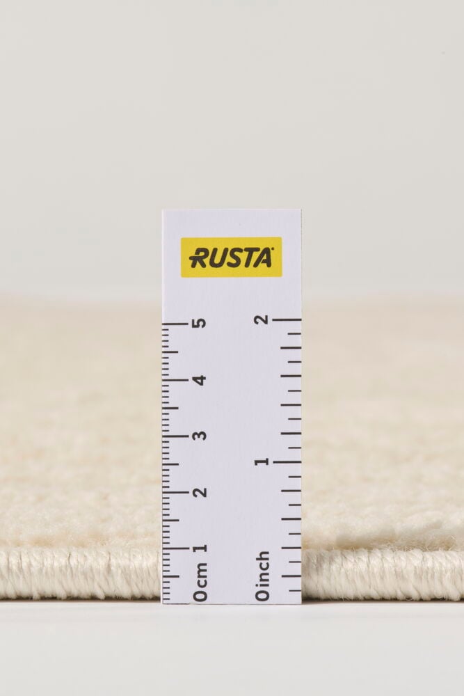 Lähikuva luonnonvalkoisesta polypropeeni Matto Tindra -matosta, mittaviivaimella mittaamassa nukan korkeutta.