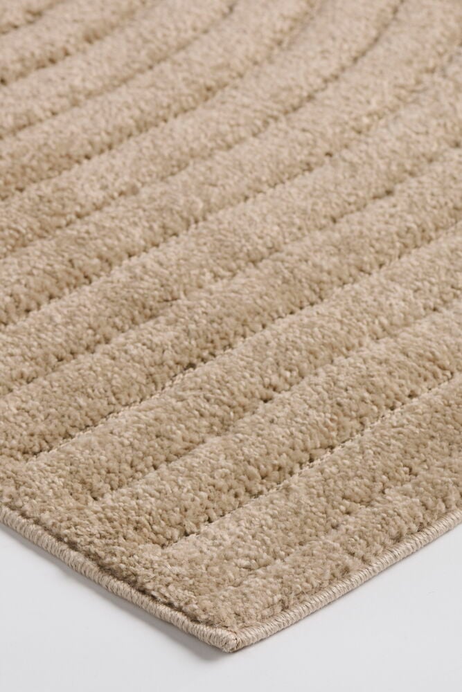 Beige Tindra polypropeenimatto, jossa on uurrettu pinta ja siististi viimeistellyt reunat.