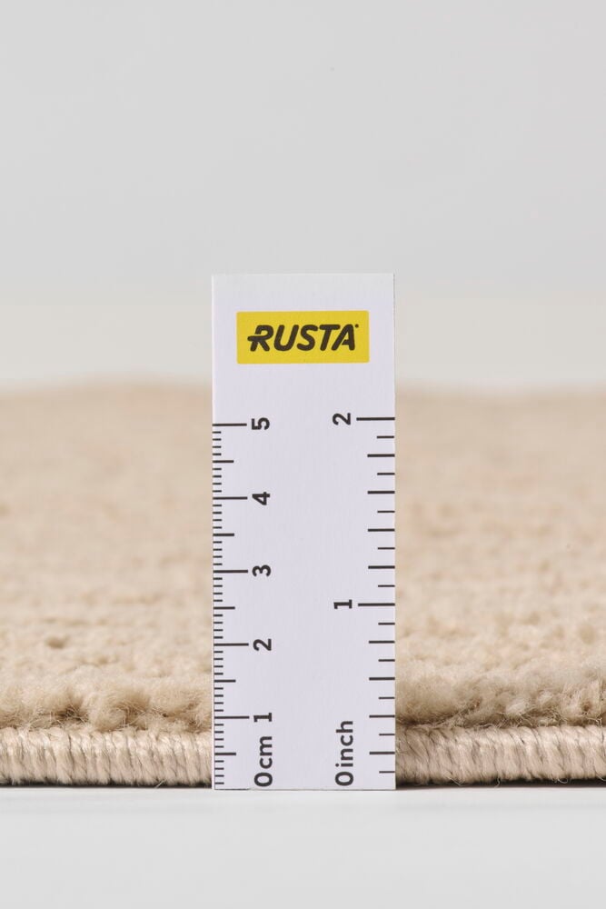 Lähikuva beigestä polypropeenimatosta Tindra, näyttää tekstuurin ja noin 1,5 cm nukankorkeuden viivoittimella.