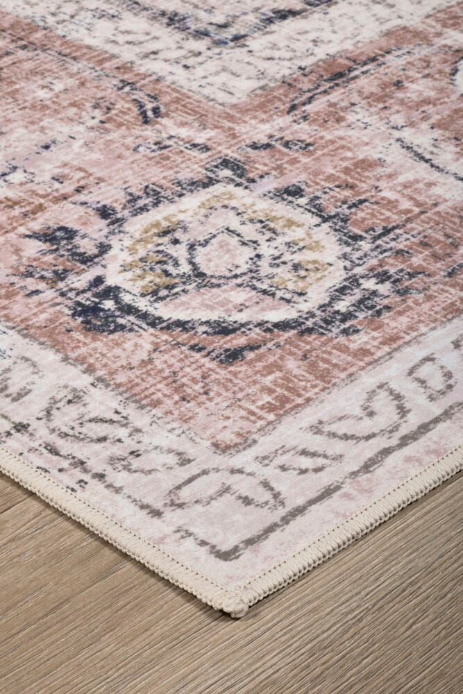 Vinklad närbild av en Matta Clara Rost Polyester med slitet traditionellt mönster i rost, ljusbeige och mörkblått.