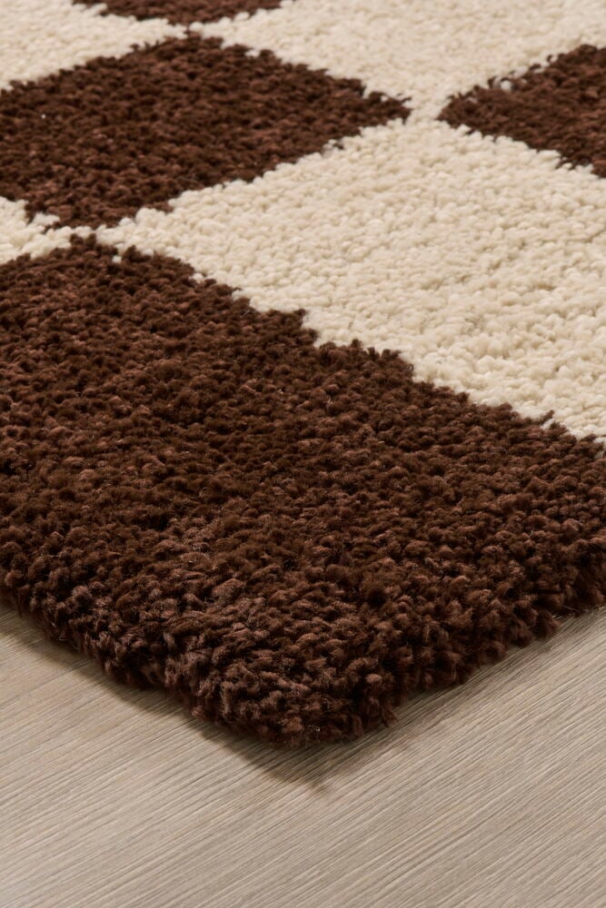 Ruskea ja valkoinen ruutukuvioitu pehmeä matto.