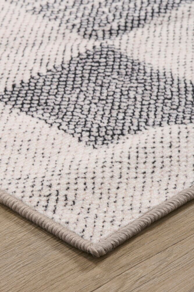 Lähikuva harmaanvalkoisesta matosta, jossa on geometrinen kuvio.