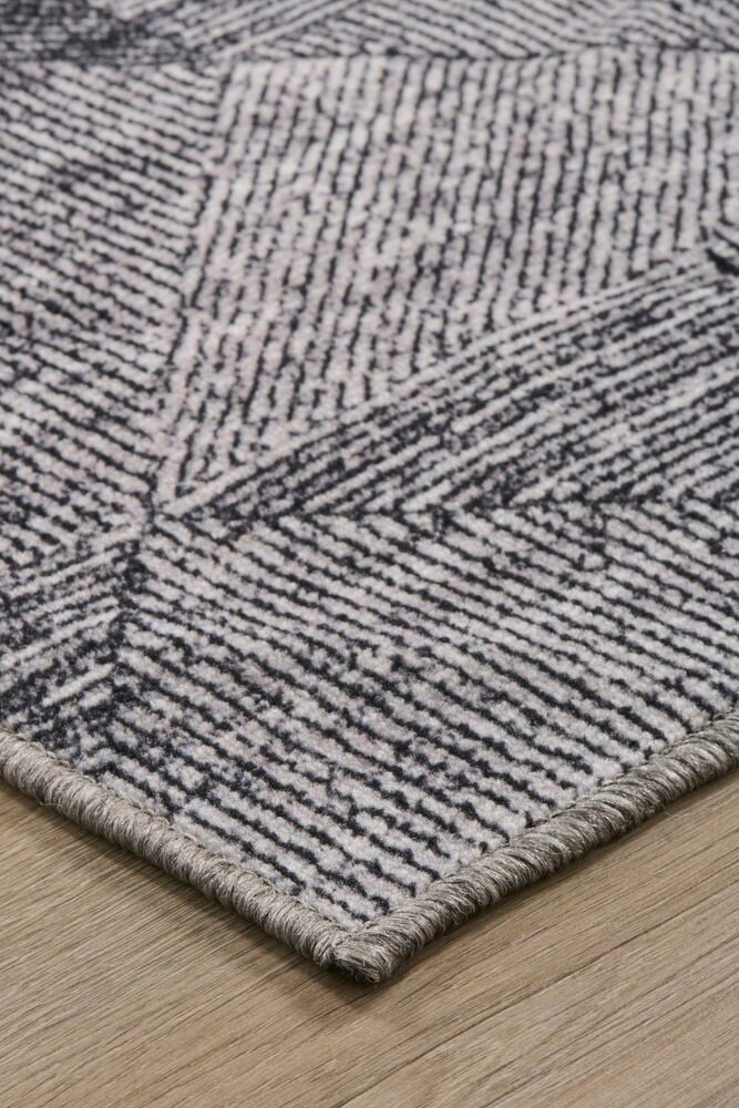 Hörnet av en mörkgrå matta med mönster.