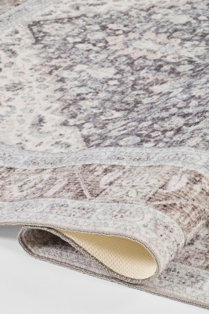 Ein mehrfarbiger Polyamid-Teppich mit komplexem Muster, teilweise gerollt, um die Anti-Rutsch-Unterseite zu zeigen.