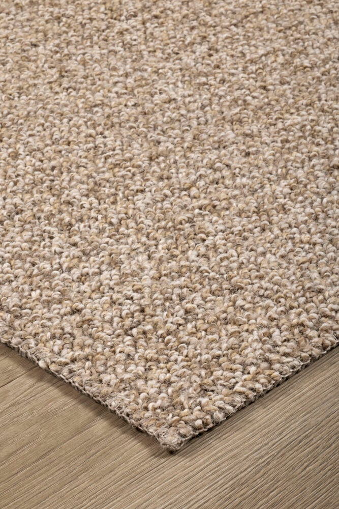 Beige løkketeppe på et lyst brunt tregulv.