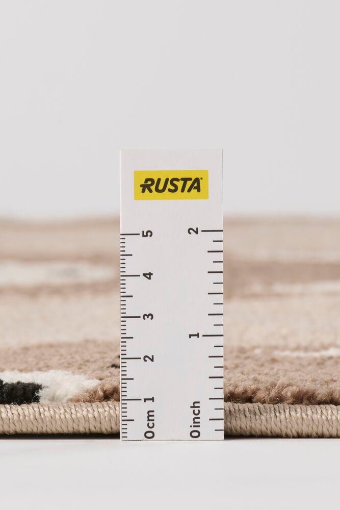 Lähikuva Beige Polypropeeni matosta, jossa matala nukka ja beigejä, mustia, valkoisia kuvioita, mitattu viivaimella.