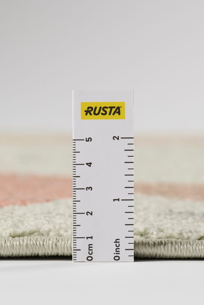 Närbild på en Multifärgad Polypropen-matta, vit med rosa mönster, mätt till 1,5 cm tjocklek.
