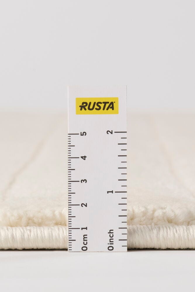 Lähikuva Kerma-matosta ja viivaimesta, joka osoittaa sen paksuutta senttimetreinä ja tuumina.