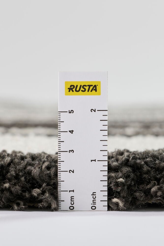 Lähikuva antrasiitin värisestä polypropeenimatto Wilmasta, jossa viivain näyttää sen korkean nukan korkeuden.