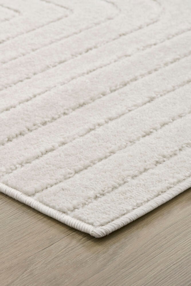 Vit gångmatta med diskret mönster på trägolv.