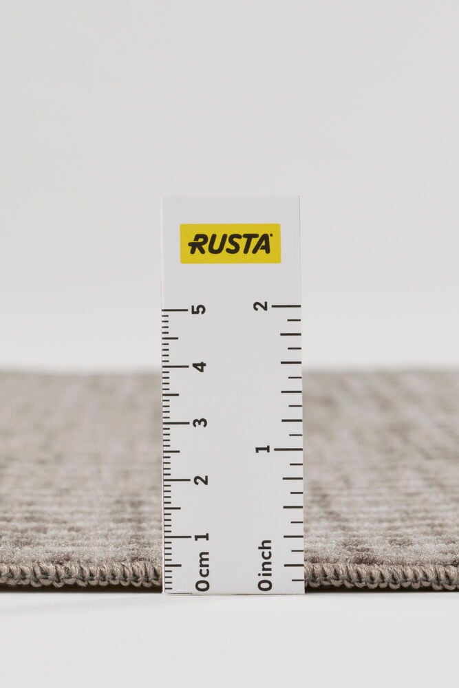 Närbild i sidoprofil av en brun gångmatta Nellie i polyamid, visar vävd textur och tjocklek mätt med linjal.