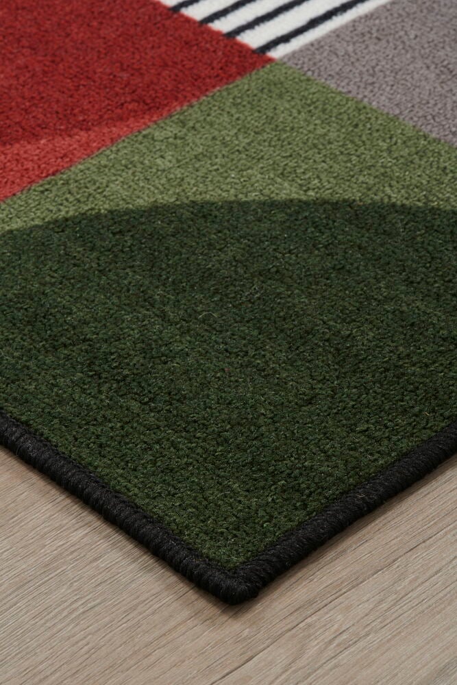 Hörnet av en multifärgad matta på trägolv.