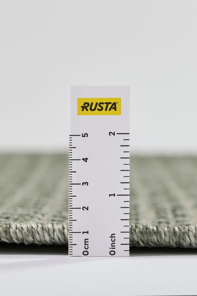 Närbild från sidan av en grön gångmatta Hilda i polypropen med måttstock som mäter dess tjocklek.