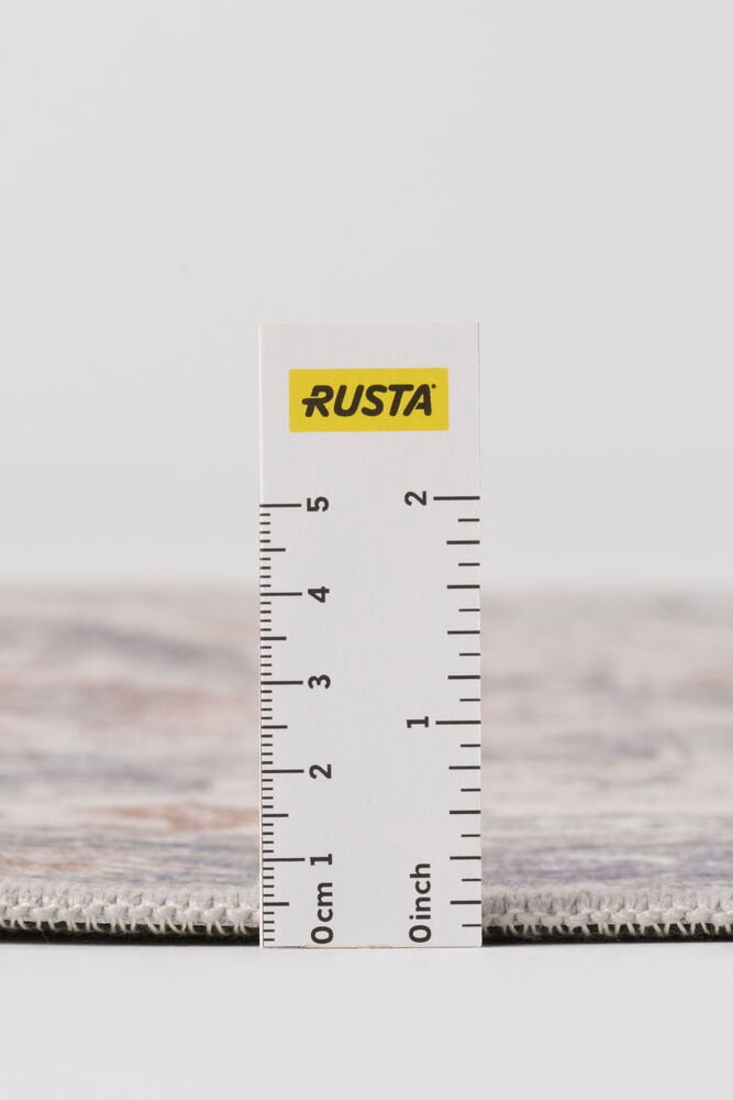 Lähikuva sivukuva Harmaa Polyesteriä matosta, jossa on hienovarainen kuvio, mitattuna mittaviivaimella mittakaavaa varten.