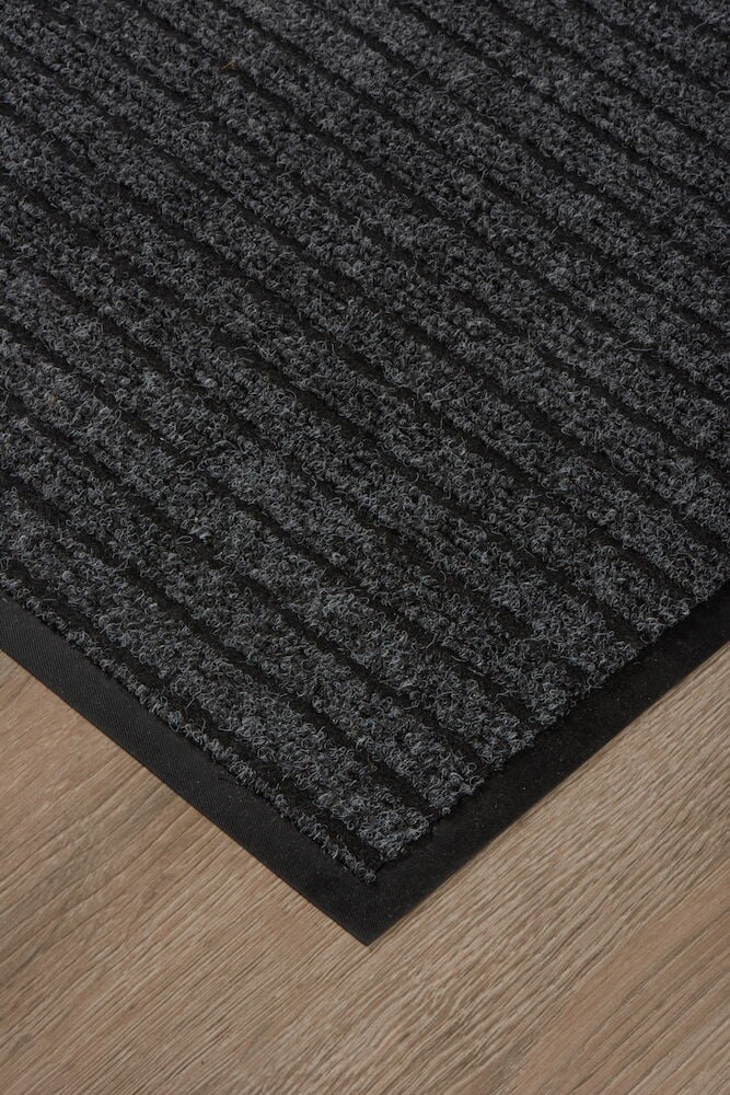 Tummanharmaa ovimatto, jossa on kumipohja puulattialla.