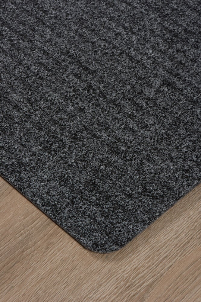 Harmaa ovi- tai lattiamatto polypropeenista puulattialla.