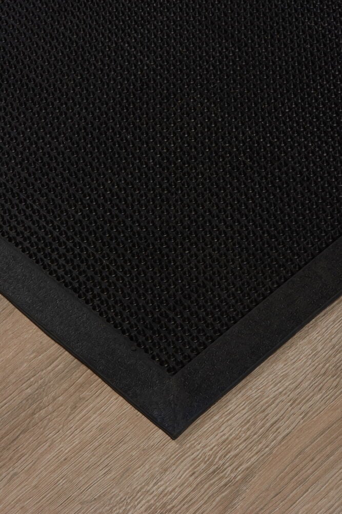 Svart dörrmatta med mönstrad yta på trägolv.