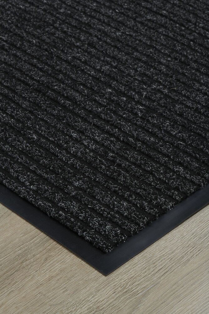 Tummanharmaa ovimatto, jossa on uurrettu pinta ja kumireuna.