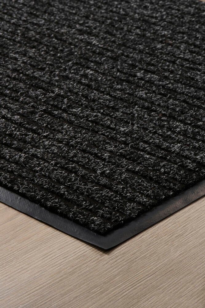 Tummanharmaa ovimatto, jossa on raitoja puulattialla.