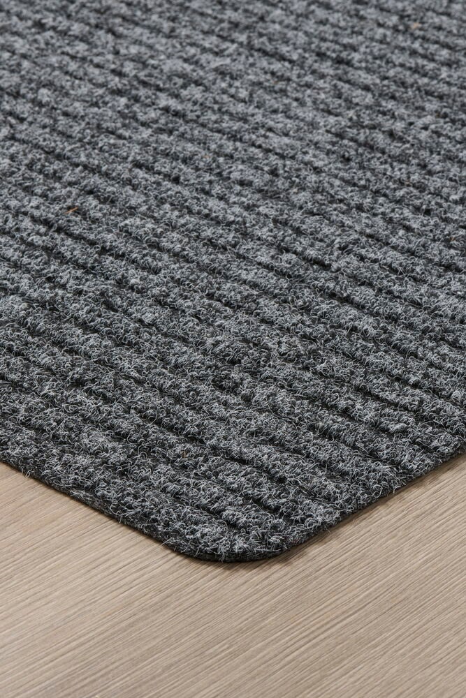 Harmaa ovimatto polyesteristä puulattialla.